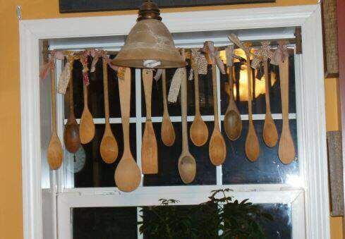 Decoración de cocina con cucharas de madera colgadas en una ventana.