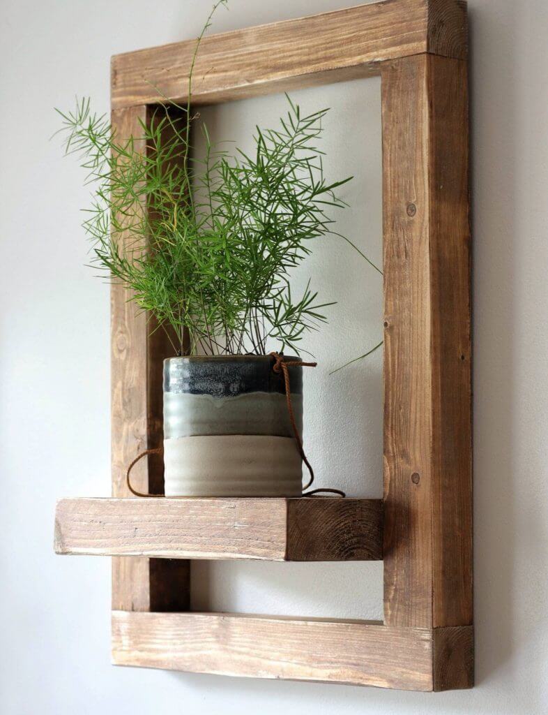 Estilo Country: Macetero de madera con marco y planta verde, diseño minimalista para interiores.