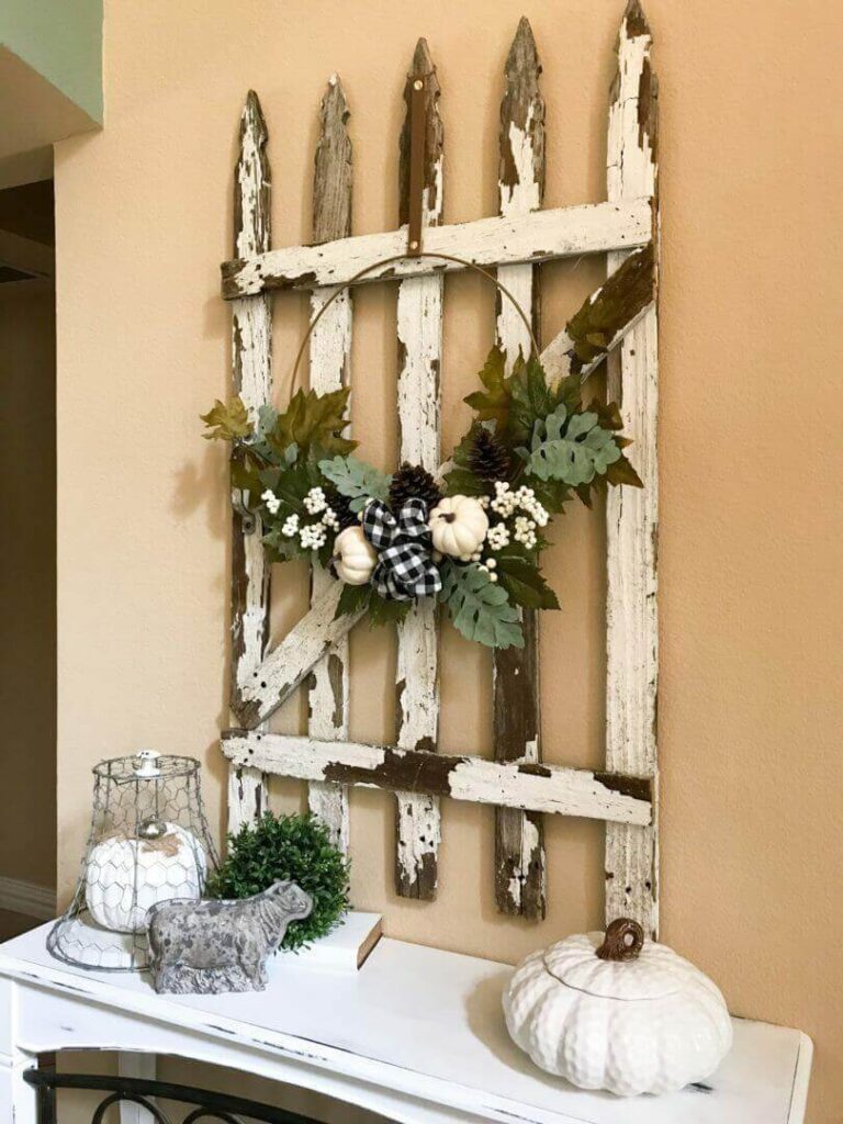 Estilo Country: Decoración rústica con puerta de madera antigua, guirnalda de otoño y accesorios como calabazas blancas y lámpara de hierro