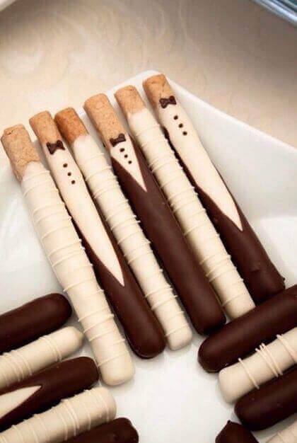 Elegantes palitos de galleta cubiertos de chocolate blanco y oscuro como novios, ideales postres para bodas.