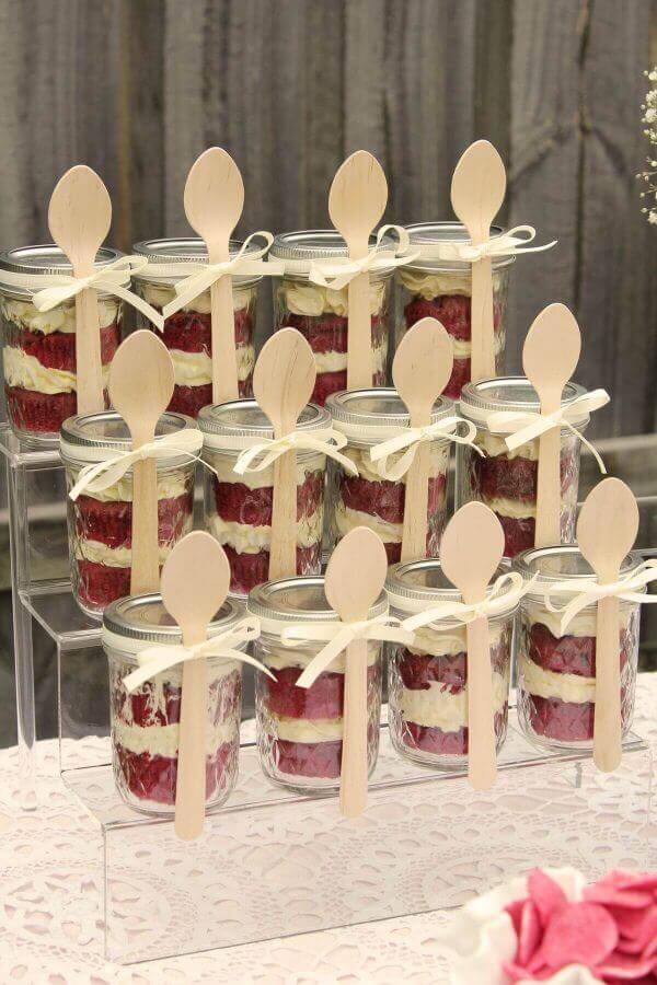 Pastel de terciopelo rojo en mini tarros de vidrio con cucharas de madera para boda rústica.
