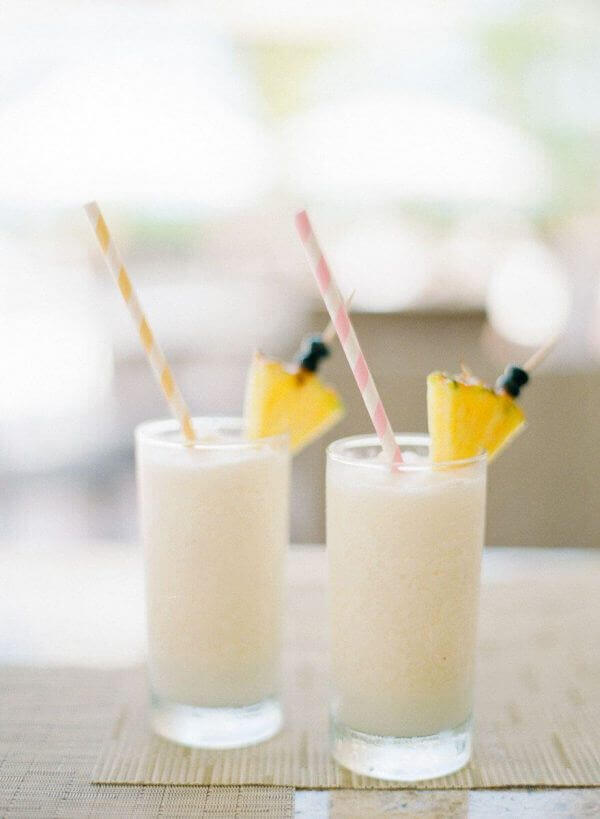 Dos vasos de piña colada helada, bebida de boda refrescante y tropical con frutas.