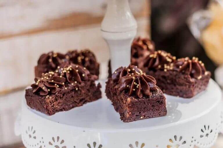 Deliciosas porciones de brownie de chocolate con glaseado cremoso y chispas doradas, un postre clásico.