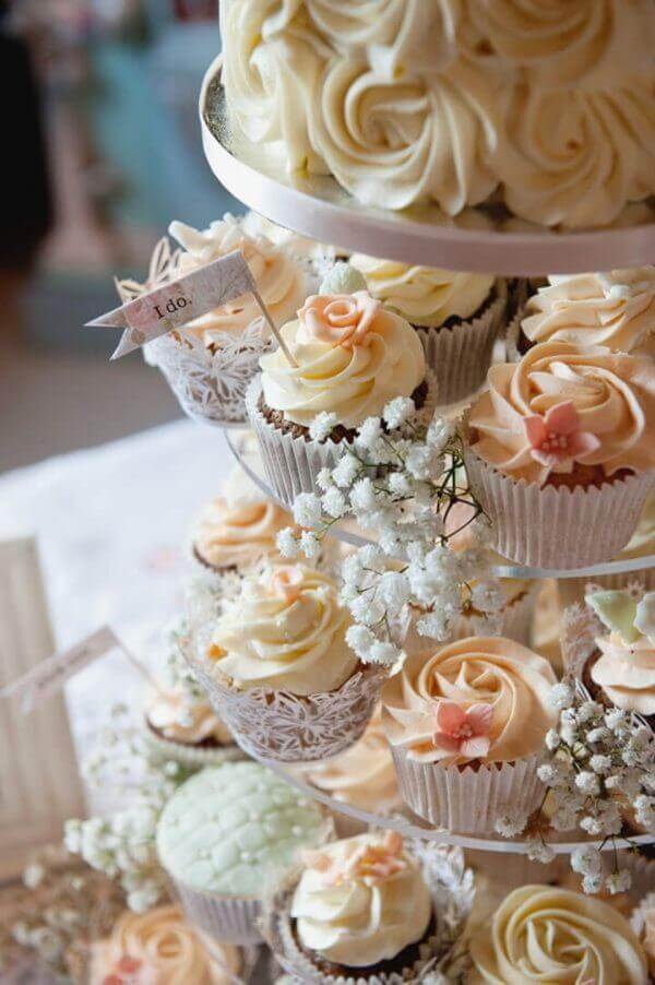 Elegante torre de cupcakes decorados con crema y flores, perfecto postre para bodas