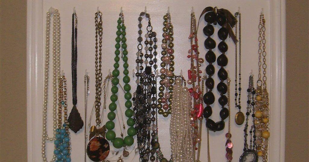 Ideas prácticas para el hogar: Collares de cuentas y perlas colgados ordenadamente en panel blanco.