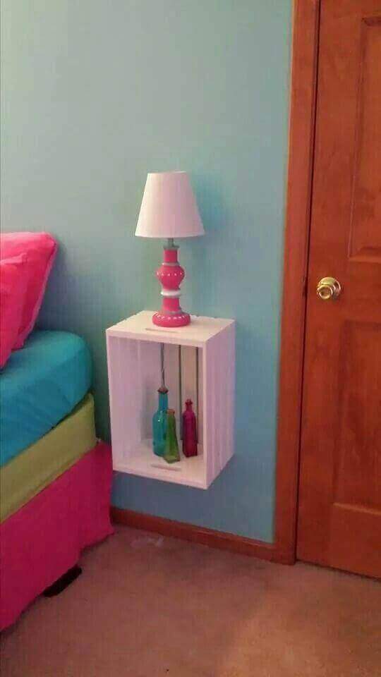 Rincón de dormitorio decorado: Cama colorida junto a estante de pared con botellas decorativas y lámpara rosa.