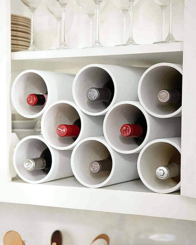 Almacenaje decorativo: Botellas de vino en estante con copas y platos sobre superficie de madera.