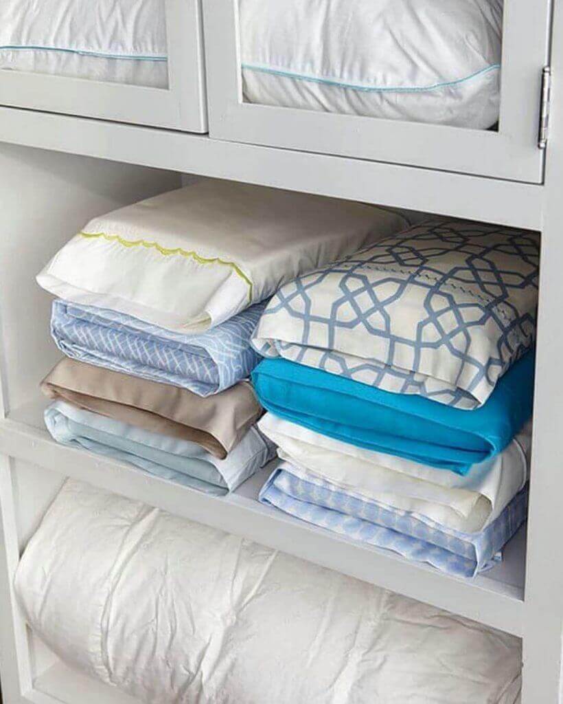 Ideas prácticas para el hogar: Ropa de cama doblada y organizada sobre estantería blanca
