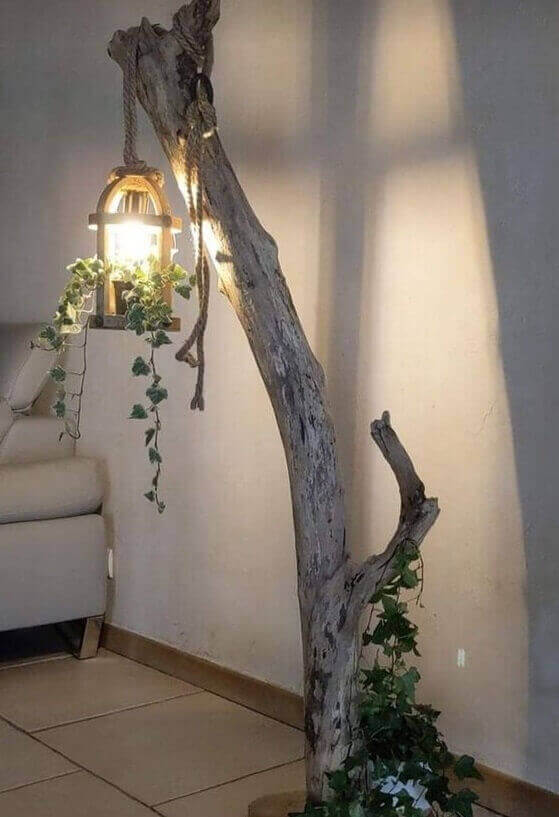 Lámparas con troncos y cuerda rústica junto a sofá beige en ambiente cálido y natural.